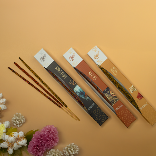 Charu Perfumery incense stick boxes in Kasturi, Kusth, Classic Chandan, and Amber fragrances displayed with incense sticks and flowers on a warm beige background.